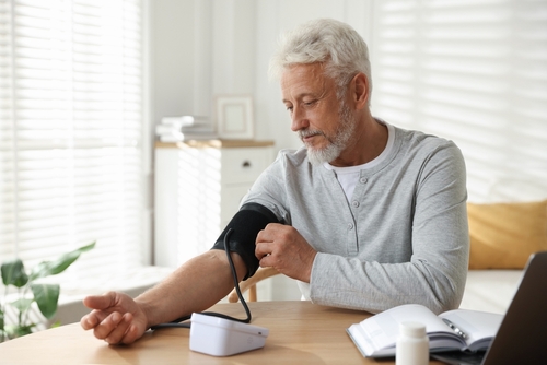 Senior man checking blood pressure at home with digital monitor to manage hypertension and reduce type 2 diabetes risk